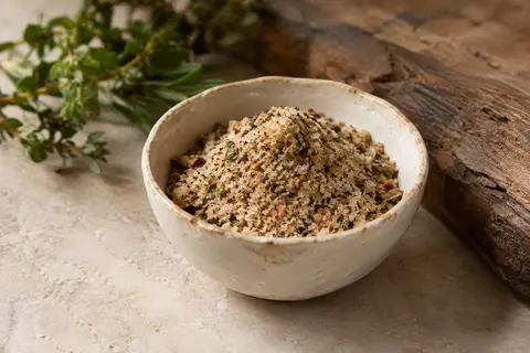 Sel marin aromatisé aux herbes et légumes présenté en poudre dans une coupelle en céramique