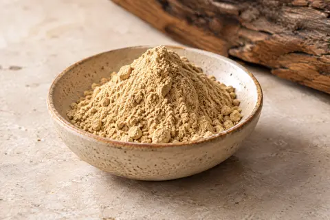 Poudre de gingembre beige doré dans une coupelle en céramique sur une pierre claire
