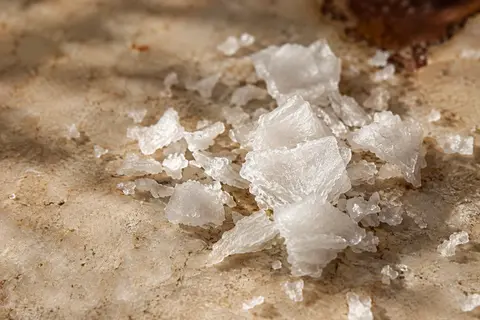 Flocons blancs et irréguliers de sel marin écossais disposés sur une pierre claire