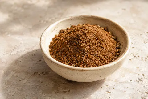 Mélange en poudre pour pain d’épices dans une coupelle en céramique sur une pierre claire