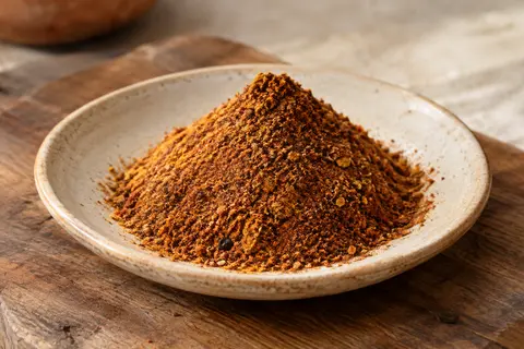 Mélange ras el-hanout aux tons chauds présenté sur une céramique artisanale claire.